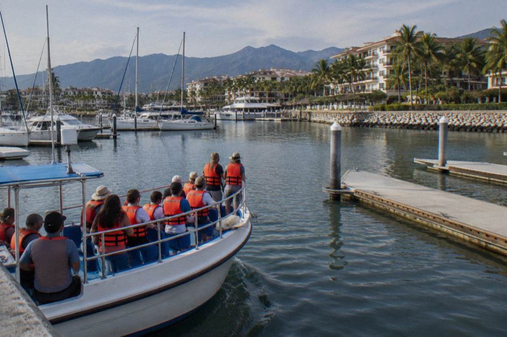 Passengers in life vests watching open water from the bow of a whale watching boat
