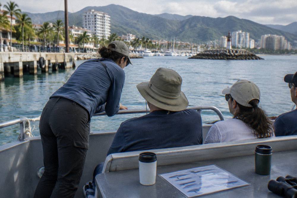 A marine biologist talking with passengers on the deck of a whale watching boat