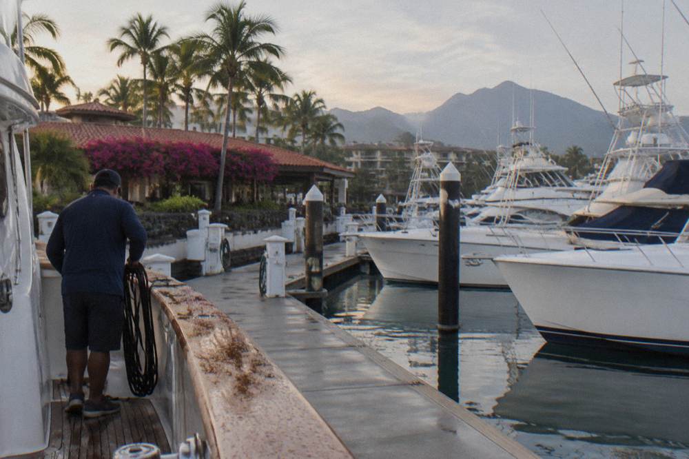 Marina boardwalk with moored boats and hills behind in early morning light