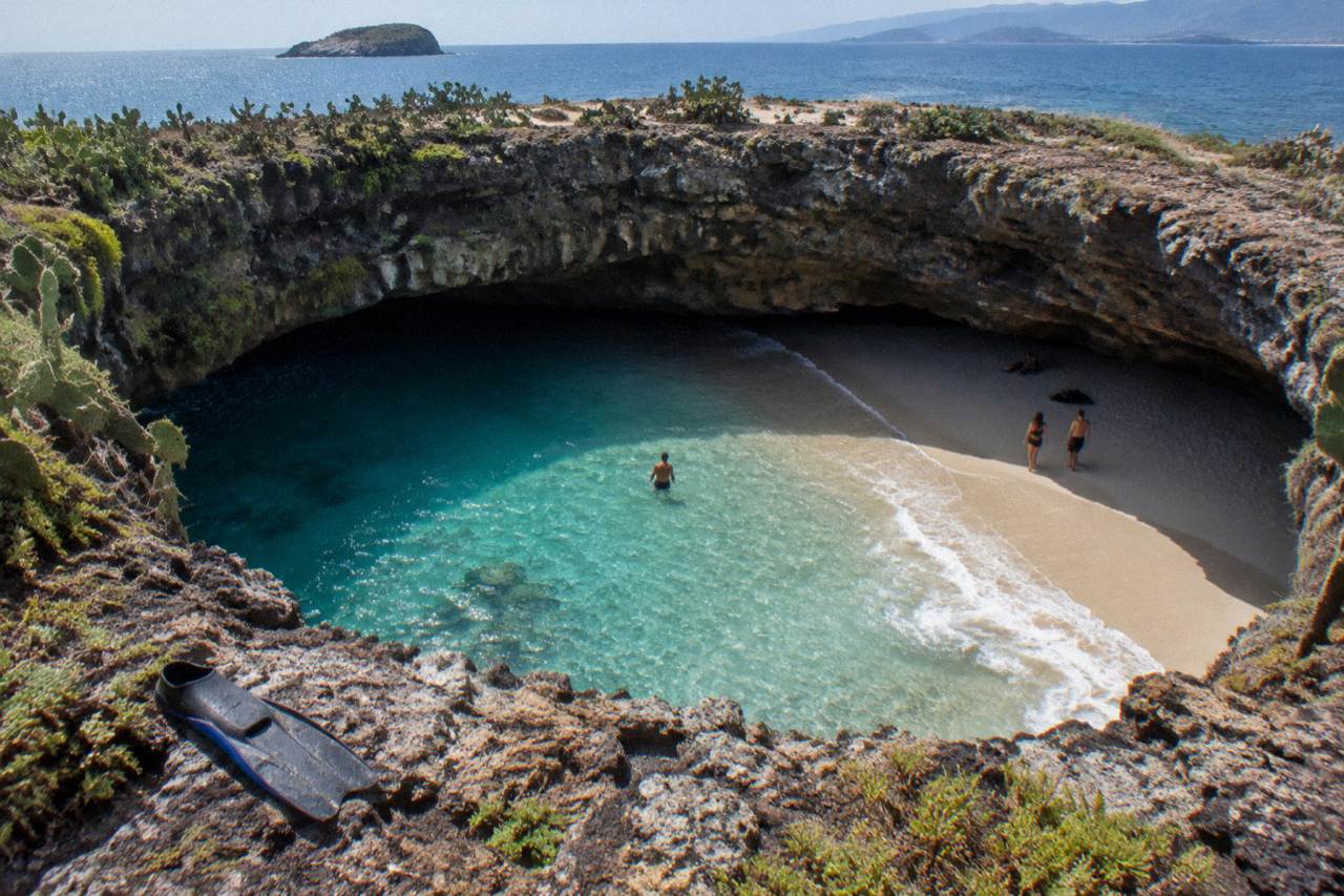 A hidden sandy beach inside a collapsed cave opening on a rocky island in Banderas Bay