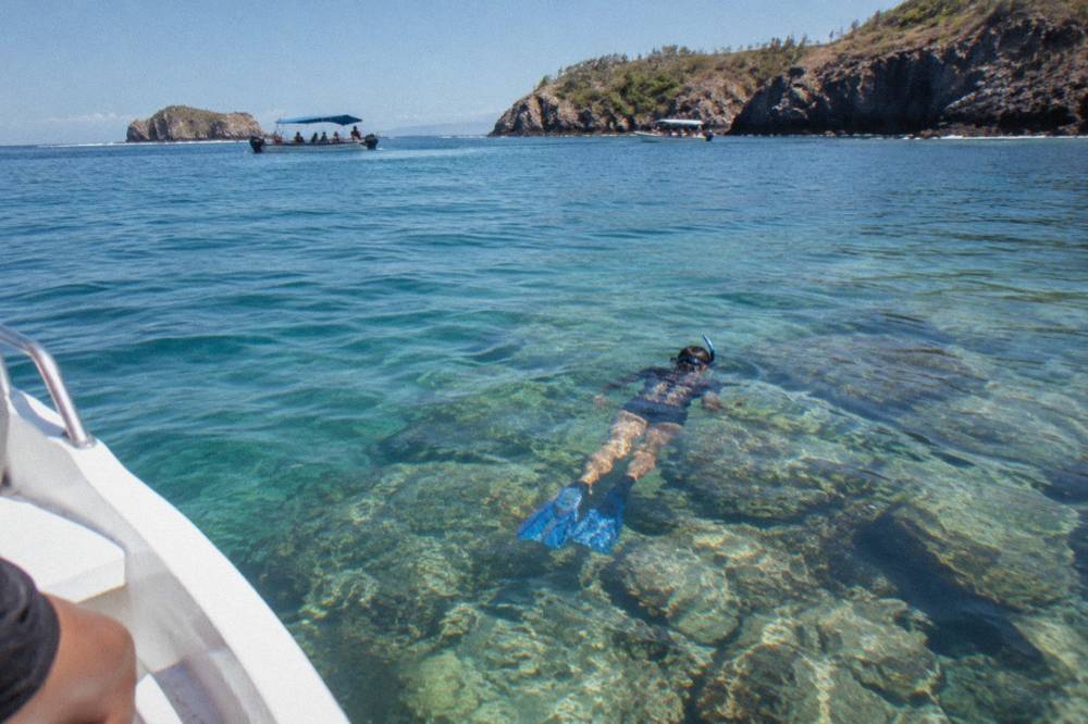 Snorkeler floating above clear shallow water above a reef