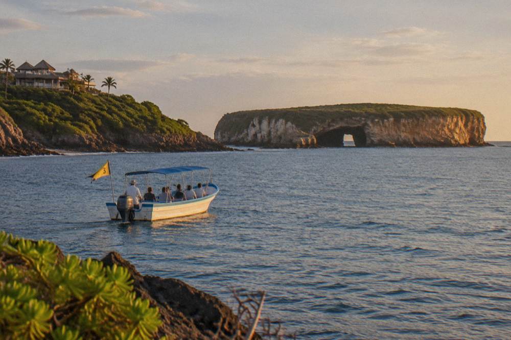 Small tour boat holding position in calm blue water near island cliffs