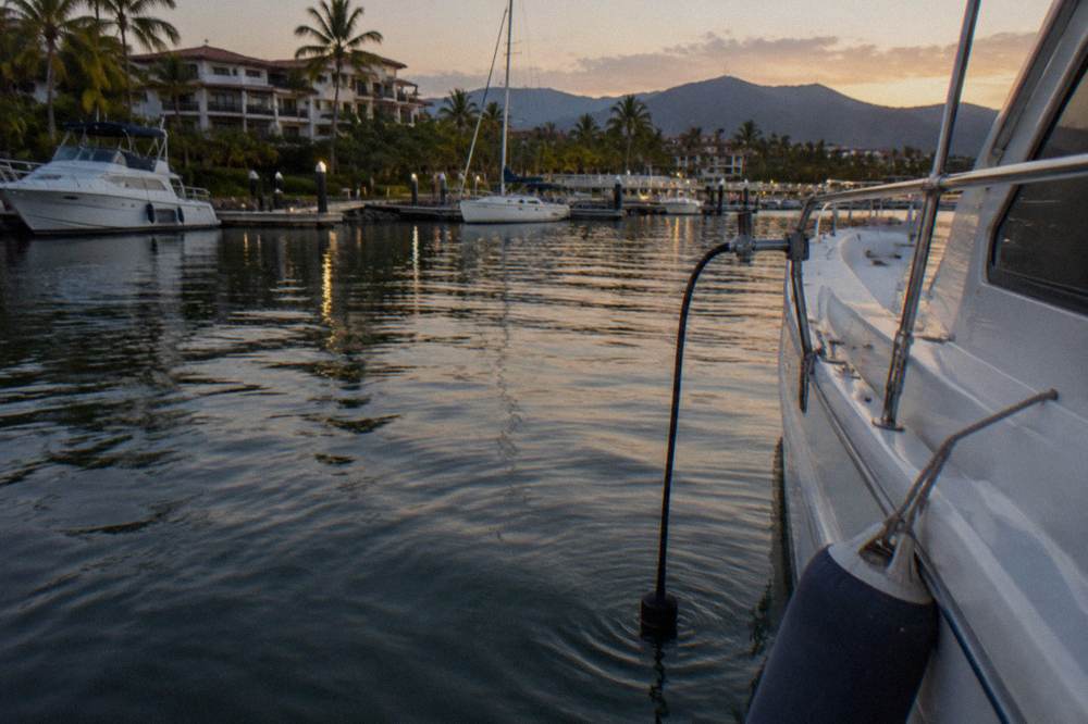 A boat at rest on open water with a hydrophone cable lowered over the side