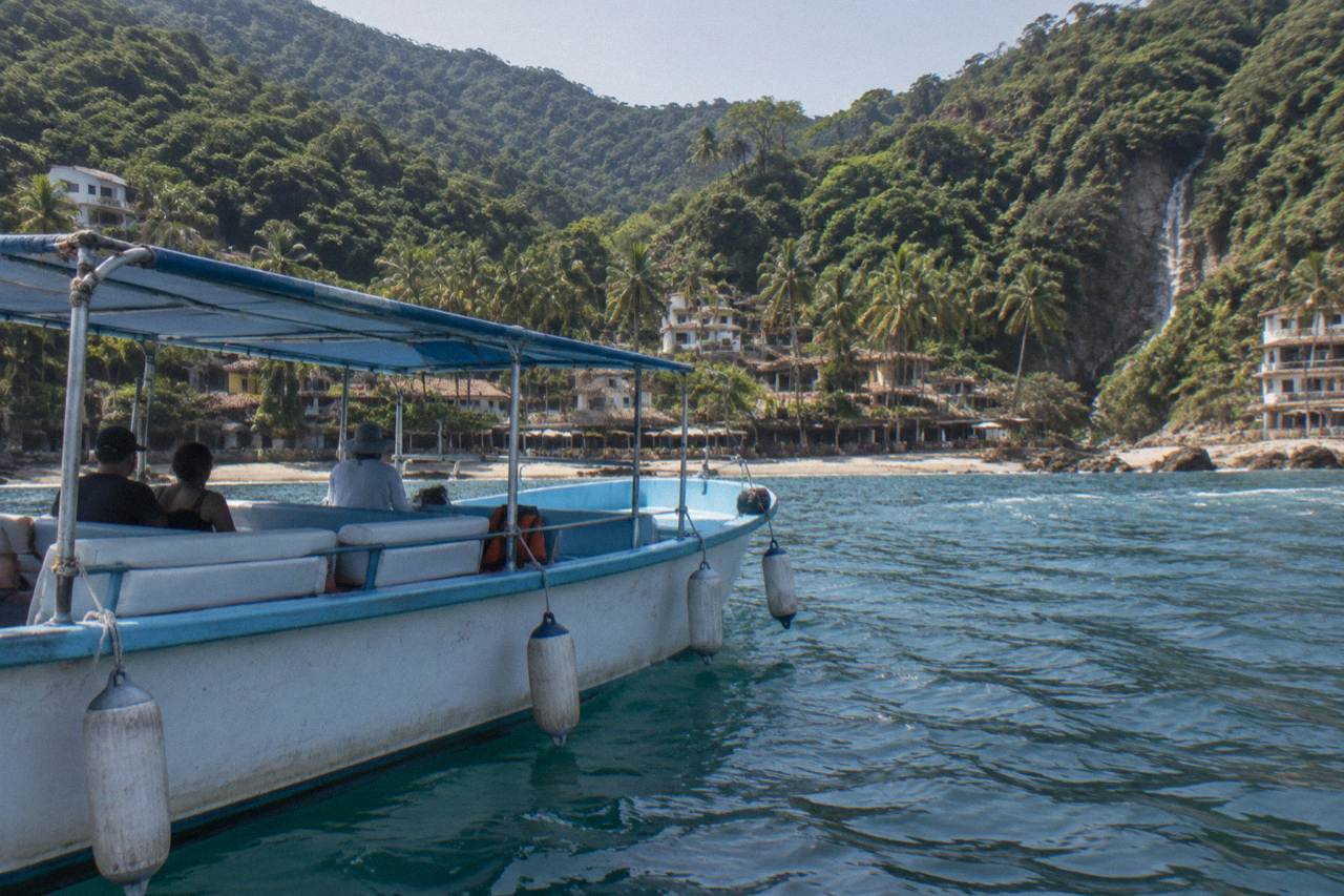 A calm whale-watching boat resting on blue water in Banderas Bay with distant green hills