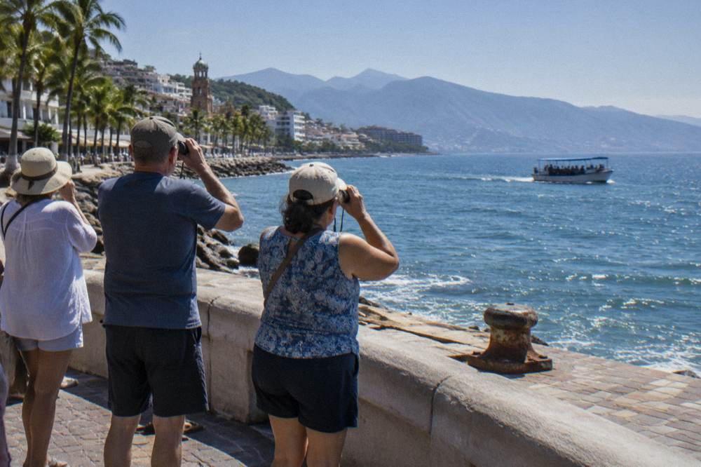 A small tour boat with passengers holding binoculars on open ocean water