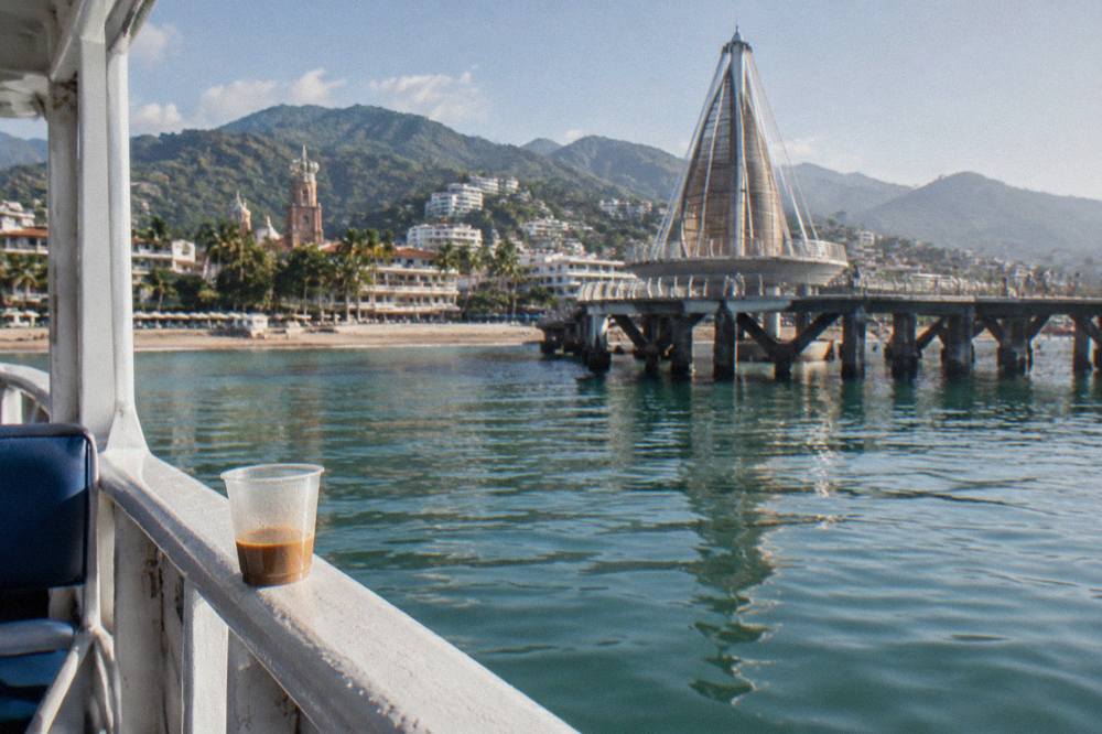 Calm green water of Banderas Bay seen from the rail of a moored tour boat in morning light