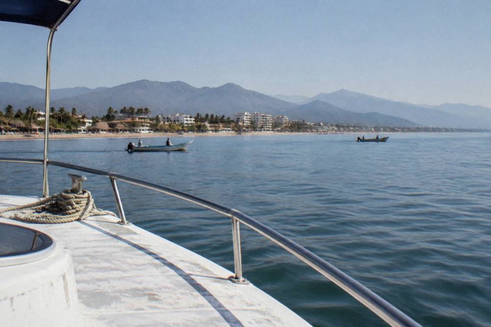 Horizon of Banderas Bay at midday with distant mountains visible across calm water from a boat deck