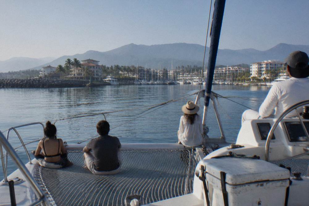Passengers rail of a whale watching catamaran at rest on still blue water with distant hazy coastline