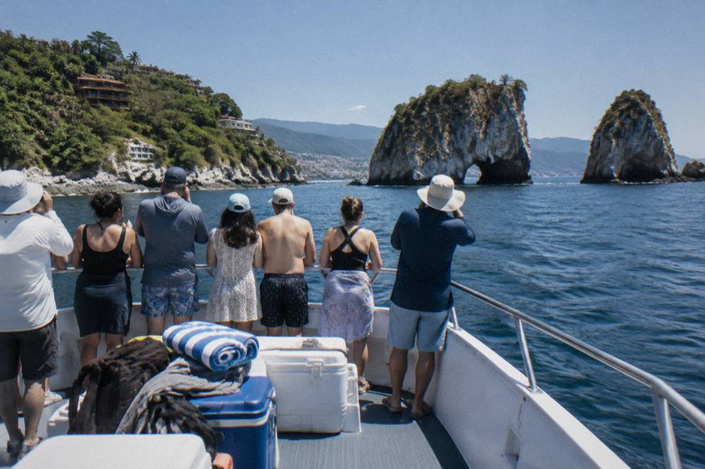 A whale watching boat at idle with passengers standing along the rail looking out at open water