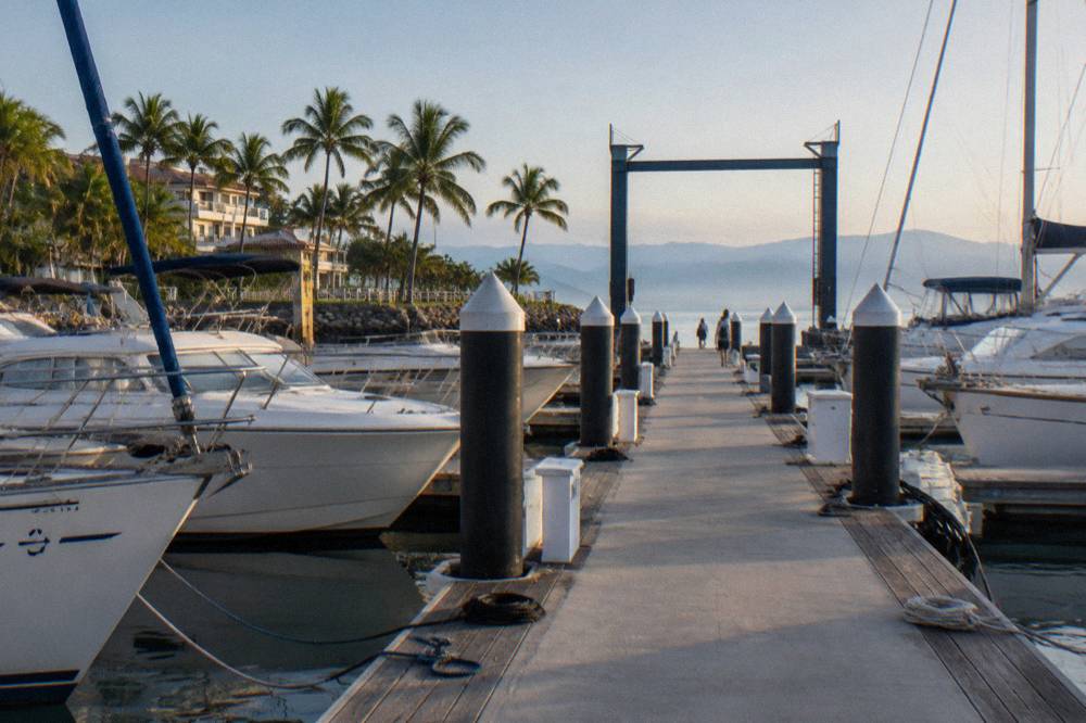 A marina boardwalk lined with boats moored at their slips in early morning light