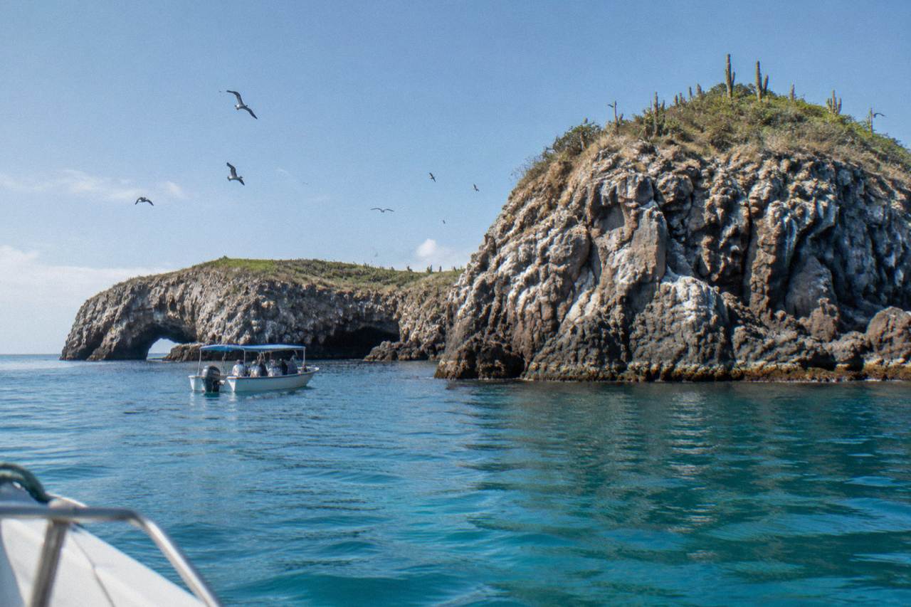 Rocky islands rising from calm blue water with a small tour boat nearby