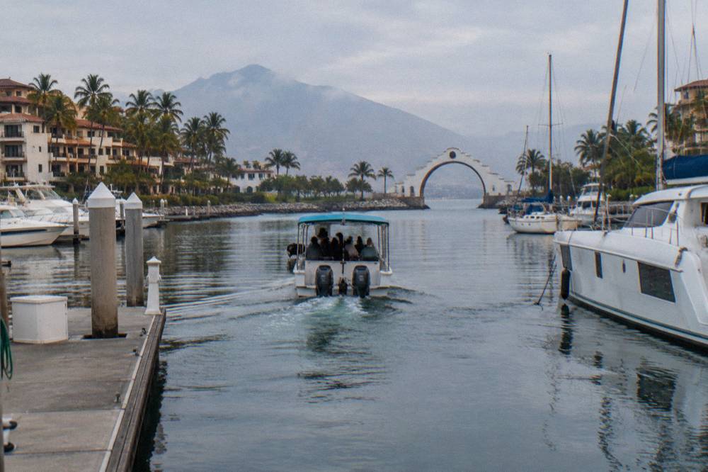 A small tour boat easing away from a dock into open bay water