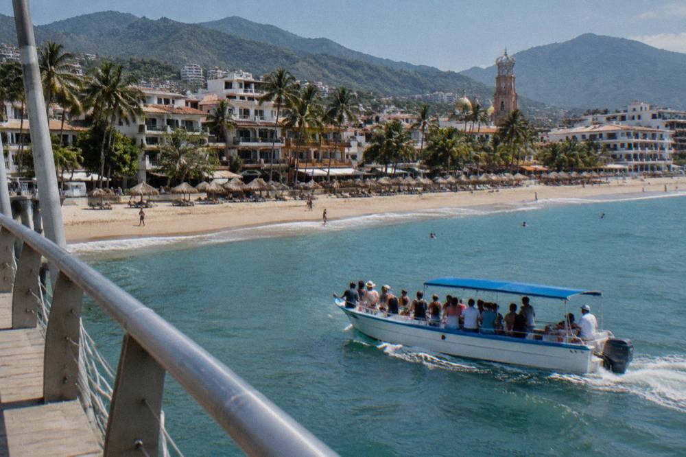 A shared whale watching boat with passengers along the rail in Banderas Bay