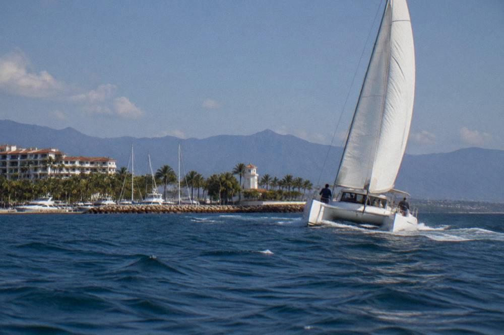 A catamaran under sail in Banderas Bay with distant mountains