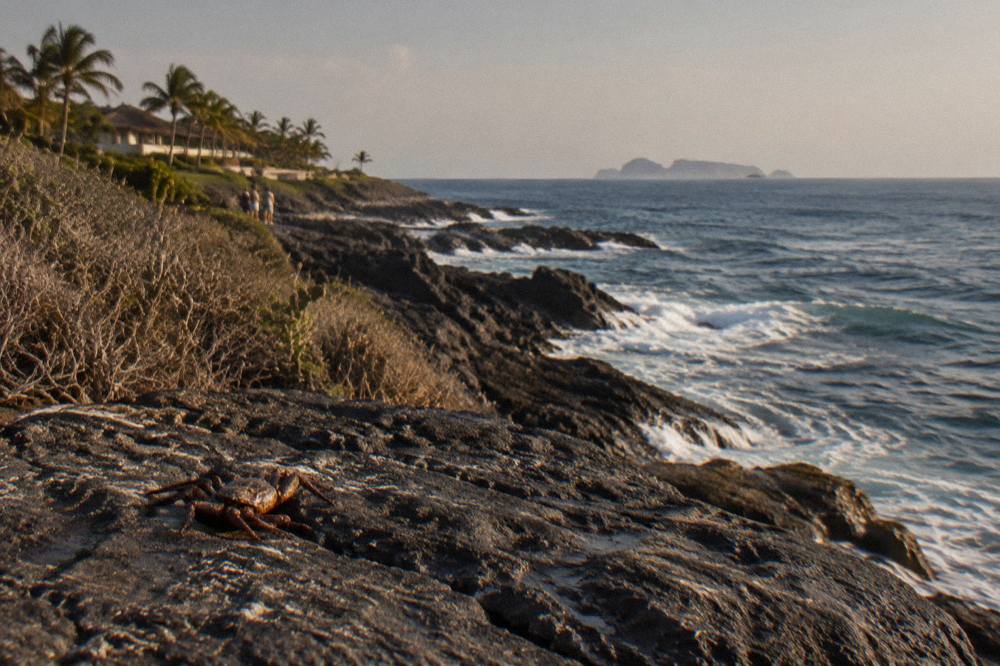 Rocky point extending into blue ocean with distant islands on the horizon