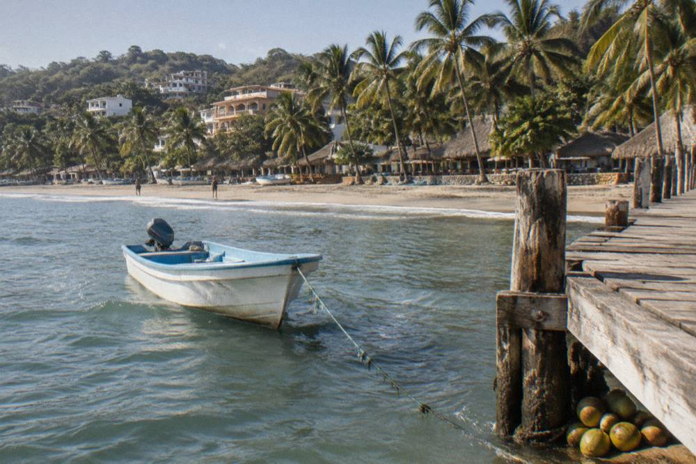 Small boat anchored beside a wooden pier in a small Pacific coast harbor