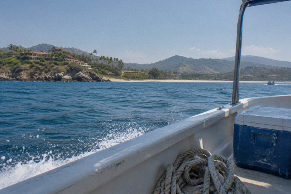 Tour boat on open blue water with hilly coastline in the distance