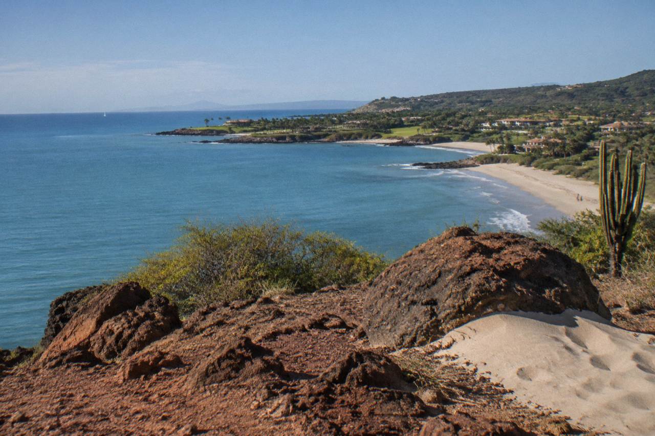 Calm blue water of northern Banderas Bay with a rocky peninsula and low green hills