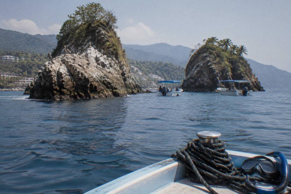 Granite rock islands rising from calm blue ocean with snorkel boats anchored nearby