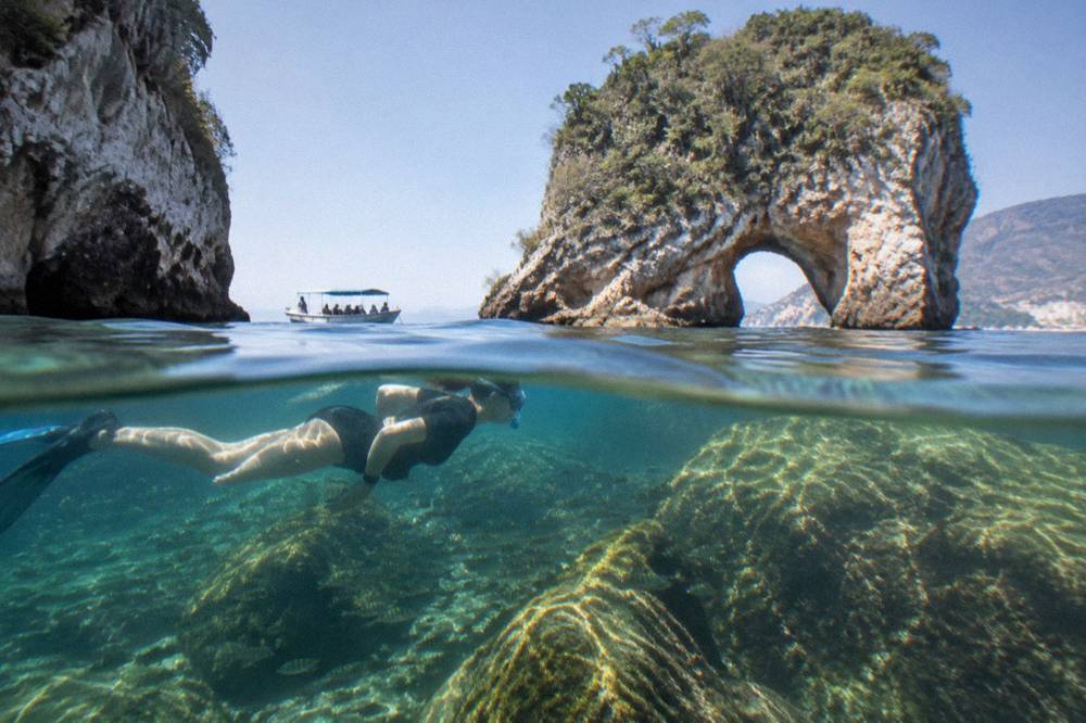 Snorkeler floating above a rocky reef in clear sunlit water