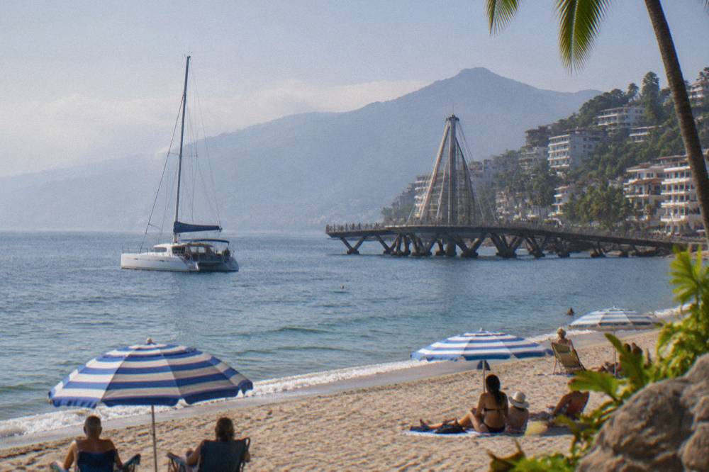 A catamaran anchored near the Puerto Vallarta shoreline with passengers on deck