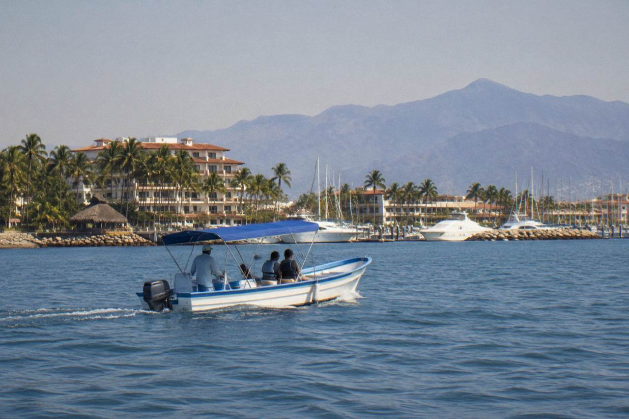 A small whale watching boat on calm blue water in Banderas Bay with hills in the distance