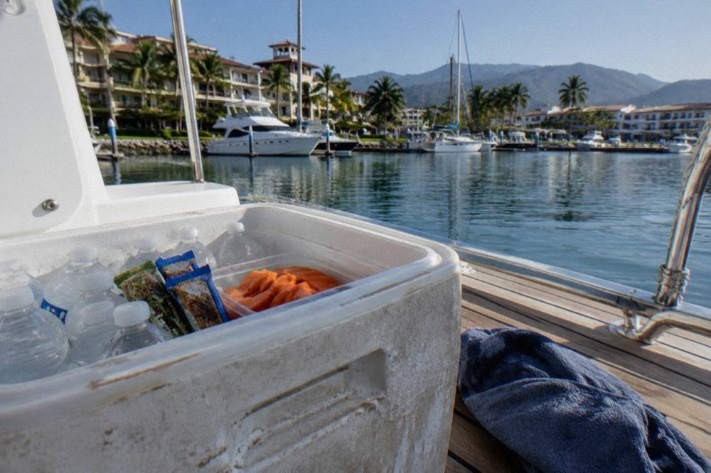 An open cooler with water bottles, granola bars and fruit packed for a boat trip