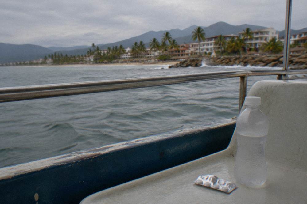 A packet of motion sickness tablets and a bottle of water resting on a boat bench seat
