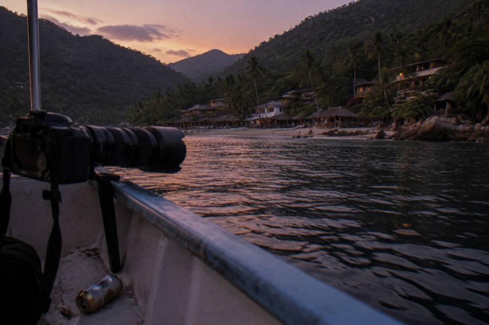 A camera with a telephoto lens held steady on a boat rail